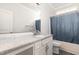 Well-lit bathroom with granite countertop vanity and full tub with blue curtain at 1828 Wellspring Ct, Graham, NC 27253
