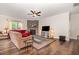 Cozy living room featuring hardwood floors, a stone fireplace, a ceiling fan, and ample natural light at 1828 Wellspring Ct, Graham, NC 27253