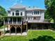 Back exterior with a large deck, screened-in porch, and lush green lawn under a blue sky at 225 Midenhall Way, Cary, NC 27513