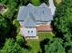 Aerial view of a backyard with a deck, covered patio, and a lush lawn surrounded by mature trees at 225 Midenhall Way, Cary, NC 27513