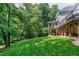 Green backyard with house exterior featuring a wooden deck and stairs surrounded by a lush forest at 225 Midenhall Way, Cary, NC 27513