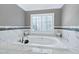 Bathroom with a luxurious soaking tub surrounded by marble and gray walls at 225 Midenhall Way, Cary, NC 27513