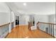 Bright upstairs hallway with wood floors and a wood railing with a black metal baluster at 225 Midenhall Way, Cary, NC 27513