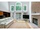 Light-filled living room features hardwood floors, a fireplace, and large windows offering views of the surrounding greenery at 225 Midenhall Way, Cary, NC 27513