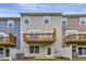 Back exterior view of townhomes featuring wood decks, white fence, and neatly kept lawn at 2299 Bay Minette Sta # 537, Apex, NC 27502