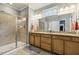Modern bathroom with granite countertop, wooden cabinets, glass-enclosed shower, and ample natural light at 2410 Kinglass Dr, Fuquay Varina, NC 27526