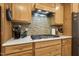 Close up of a well-equipped kitchen with a gas stovetop, mosaic backsplash, and ample wood cabinetry at 2410 Kinglass Dr, Fuquay Varina, NC 27526