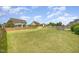 Wide view of the expansive, fenced backyard featuring a well-maintained lawn and stone fire pit at 2507 Belvinwood Dr, Fuquay Varina, NC 27526