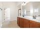 Bright bathroom featuring double sinks, wood cabinets, tile floors, and natural light at 2507 Belvinwood Dr, Fuquay Varina, NC 27526