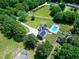 Expansive aerial view of a home with a large in-ground pool, solar panels, and ample green space surrounded by mature trees at 2709 Les Paul Ln, Apex, NC 27539