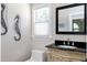 Half bathroom featuring black granite countertop vanity and custom seahorse wall decor at 2709 Les Paul Ln, Apex, NC 27539