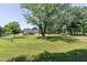 Scenic view of a home with a sprawling front yard, mature trees, and a long driveway leading to the charming residence at 2709 Les Paul Ln, Apex, NC 27539