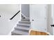 A well-lit staircase with carpeted steps and a hardwood landing features a nearby door at 2709 Les Paul Ln, Apex, NC 27539