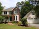 Charming front exterior boasts brick accents, a welcoming porch, mature trees, and a detached garage at 3137 Falling Cedars Dr, Chapel Hill, NC 27516