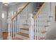 Elegant staircase featuring hardwood steps, white railings, and decorative newel posts at 418 Wyndham Drive, Chapel Hill, NC 27516