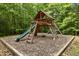 Wooden playground set with slide, swings, and climbing structure, set in a wooded area at 4312 Mystic Ln, Hillsborough, NC 27278