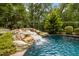 Inviting pool area with rock waterfall feature, surrounded by lush greenery and landscaping at 4312 Mystic Ln, Hillsborough, NC 27278