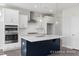 Modern kitchen featuring white cabinetry, stainless steel appliances, large island, and a stylish vent hood at 444 Golden Dragonfly St, Wake Forest, NC 27587
