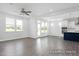 Open-concept living room featuring gray wood flooring, ceiling fan, natural light, and view into the kitchen at 444 Golden Dragonfly St, Wake Forest, NC 27587