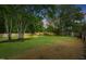 Large backyard area with mature trees, a wood storage pile, and a shed, ideal for outdoor activities at 5129 Neighbors Rd, Mebane, NC 27302