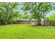 Lush backyard with mature trees, and a brick home exterior with a view of the well-manicured lawn at 5129 Neighbors Rd, Mebane, NC 27302