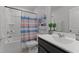 Well-lit bathroom featuring a vanity, toilet, shower-tub combo, and colorful striped shower curtain at 6415 Mentor Pl, Raleigh, NC 27616