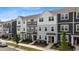 View of modern townhomes with grey and white exteriors, stone accents, and well-manicured lawns at 6415 Mentor Pl, Raleigh, NC 27616
