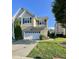 Charming two-story home with a white garage door, brick accents, green grass and mature tree at 7241 Terregles Dr, Raleigh, NC 27617