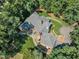 Aerial view of home with a large roof, brick chimney, patio, and walkway through mature trees and landscaping at 801 Pinehurst Dr, Chapel Hill, NC 27517