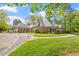 Beautiful brick home with circular driveway and manicured lawn, surrounded by mature trees at 801 Pinehurst Dr, Chapel Hill, NC 27517