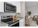 Well-equipped kitchen flowing into a living room, featuring stainless steel appliances and white cabinets at 882 John St, Clayton, NC 27520