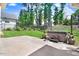 Backyard with a concrete patio and a hot tub surrounded by landscaped greenery and tall trees at 10 W Ravano Dr, Clayton, NC 27527