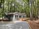 Blue one-story home with large deck surrounded by mature trees and gravel driveway at 102 Pebble Ct, Chapel Hill, NC 27516