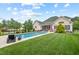 Backyard with an in-ground pool, lounge chairs, green grass, and a tree lined fence at 107 Regiment Way, Durham, NC 27705