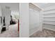 View of a carpeted walk-in closet with shelves, a hanging rod, and white walls at 107 Regiment Way, Durham, NC 27705