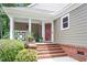 Cozy front porch featuring brick steps, white railings, a red door, and a comfortable seating area with plants at 108 Ripplewater Ln, Cary, NC 27518