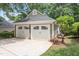 Detached two-car garage with white doors, set against a backdrop of lush greenery and a well-maintained driveway at 108 Ripplewater Ln, Cary, NC 27518