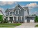 A beautiful two-story home with gray siding, white trim, a manicured lawn and an attached two-car garage at 109 Big Timber Path, Holly Springs, NC 27540