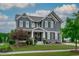 Charming home featuring gray siding, white trim, a front porch with stone accents, and a well-maintained green lawn at 109 Big Timber Path, Holly Springs, NC 27540