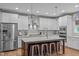 Modern kitchen features stainless appliances, marble countertops, island with seating, and pendant lighting at 109 Big Timber Path, Holly Springs, NC 27540