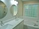 Bright bathroom featuring a double vanity, tub, and glass block window allowing ample natural light and privacy at 1104 Barrow Nook Ct, Apex, NC 27502