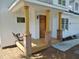 Inviting front porch with wood columns, brick bases, a wooden swing and a stained wooden door at 1104 Barrow Nook Ct, Apex, NC 27502