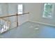 Spacious upstairs hallway featuring neutral carpet, wooden handrail, and natural light streaming from several windows at 1104 Barrow Nook Ct, Apex, NC 27502