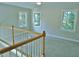 Upstairs hallway featuring three windows, neutral walls and carpet, wooden handrail, and natural light at 1104 Barrow Nook Ct, Apex, NC 27502