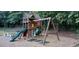 Backyard features a wooden swing set and slide in a wooded setting at 1104 Barrow Nook Ct, Apex, NC 27502