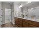Bathroom with double vanity, wood cabinets, quartz countertop, and a glimpse of the walk-in closet at 111 Chapel Run Way, Chapel Hill, NC 27517