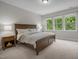 Serene bedroom featuring a wooden bed frame, soft lighting, and windows overlooking greenery at 111 Chapel Run Way, Chapel Hill, NC 27517