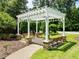 An elegant white pergola with benches is surrounded by lush greenery and a brick pathway within a beautiful community at 111 Chapel Run Way, Chapel Hill, NC 27517