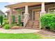 Inviting front porch with brick-based columns, wooden stairs, and lush landscaping enhancing the home's curb appeal at 111 Streamside Dr, Sanford, NC 27330