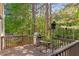 Wooden deck with outdoor dining set overlooking lush greenery and a tranquil wooded area at 112 Fairford Dr, Holly Springs, NC 27540